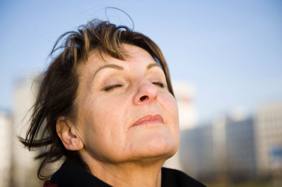 Woman outdoors with her eyes closed and face turned towards the light.