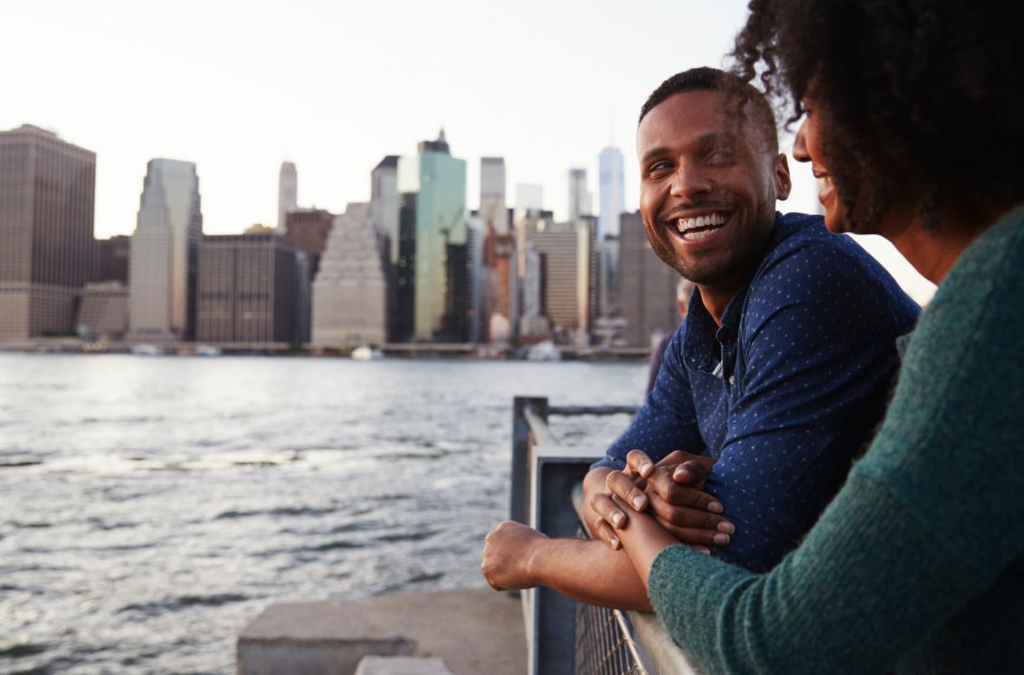 Two people talking beside a waterfront.